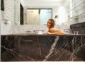 young beautiful woman is sitting in black marble bath