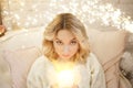 Young beautiful woman sitting with burning candles in their hands by the Christmas tree