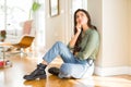 Young beautiful woman sitting on the floor at home with hand on chin thinking about question, pensive expression Royalty Free Stock Photo