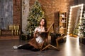 Young beautiful woman sitting on floor near christmas tree and presents Royalty Free Stock Photo