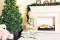 Young beautiful woman sitting on floor near christmas tree and presents on a new year eve. Interior with christmas Royalty Free Stock Photo