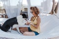 Young beautiful woman sitting on hammock with her border collie dog outdoors. Fun and summer lifestyle Royalty Free Stock Photo