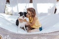 Young beautiful woman sitting on hammock with her border collie dog outdoors. Fun and summer lifestyle Royalty Free Stock Photo