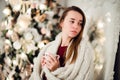 Young beautiful woman with sitting home holding cup of hot coffee wearing knitted warm sweater. Christmas tree Royalty Free Stock Photo