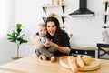 Young beautiful woman sitting at the kitchen table in the morning with her little child Royalty Free Stock Photo