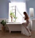 Young beautiful woman sitting near bathtub ready for taking bath near Royalty Free Stock Photo