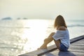 Young beautiful woman sitting on the pier enjoying sunset Royalty Free Stock Photo