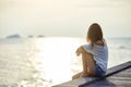 Young beautiful woman sitting on the pier enjoying sunset Royalty Free Stock Photo