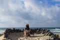 Young beautiful woman sitting on the sand surrounded of volcanic black rocks. Sea background. Horizon Canary islands Royalty Free Stock Photo