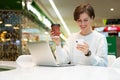 Young beautiful woman sitting at a shopping center at a table and working at a computer laptop, using mobile phone Royalty Free Stock Photo