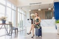 Young beautiful woman sitting on suitcases at the front desk of a hotel reception, Female traveler with bag travel luggage check- Royalty Free Stock Photo