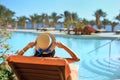 Young beautiful woman Sitting On Sun Loungers By Swimming Pool at the hotel in hat Royalty Free Stock Photo