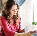 Young beautiful woman sitting at the table in a cafe and using tablet computer Royalty Free Stock Photo