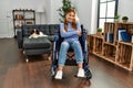 Young beautiful woman sitting on wheelchair at home happy face smiling with crossed arms looking at the camera Royalty Free Stock Photo