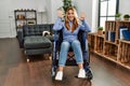 Young beautiful woman sitting on wheelchair at home showing and pointing up with fingers number ten while smiling confident and Royalty Free Stock Photo