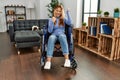 Young beautiful woman sitting on wheelchair at home very happy and excited doing winner gesture with arms raised, smiling and Royalty Free Stock Photo