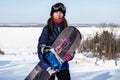 Woman in a ski mask stands on the top of a ski mountain with a snowboard Royalty Free Stock Photo