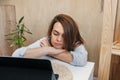 Young beautiful woman is sleeping on home office desktop in front of computer. Tired of working online. Remote work, selective Royalty Free Stock Photo