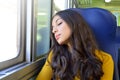 Young beautiful woman sleeping sitting in the train. Train passenger traveling sitting in a seat and sleeping