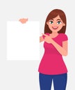 Young beautiful woman smiling and holding a blank / empty sheet of white paper or board and pointing with index finger. Royalty Free Stock Photo