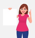 Young beautiful woman smiling and holding a blank / empty sheet of white paper or board and pointing up finger. Royalty Free Stock Photo