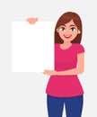 Young beautiful woman smiling and holding a blank / empty sheet of white paper or board. Woman showing a empty poster. Royalty Free Stock Photo