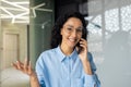 Young beautiful woman smiling and looking at camera, talking on the phone, businesswoman at workplace inside office Royalty Free Stock Photo