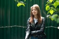 Young beautiful woman smokes outside in a black jacket