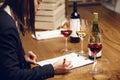 Young beautiful woman sommelier tasting red wine in the wine cellar, close up photo. Alcoholic beverages degustation