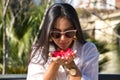 Young and beautiful woman, South American, with sunglasses and white shirt, smelling a red flower in her hands. Concept travel, Royalty Free Stock Photo