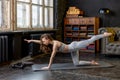 Young beautiful woman in a sport suit doing stretching exercises in a loft apartment. Sports during a pandemic on isolation,