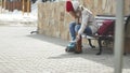 Young beautiful woman in sporty warm clothes and rollers, sitting on a wooden bench and dresses roller skates getting Royalty Free Stock Photo