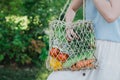 Young beautiful woman standing with ecological zero waste shopping bag with vegetables Royalty Free Stock Photo