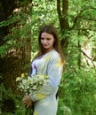 Young beautiful woman is standing in the forest with a bouquet of chamomiles Royalty Free Stock Photo