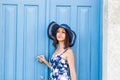 Young beautiful woman standing in front of a blue vintage entrance door Royalty Free Stock Photo