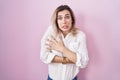 Young beautiful woman standing over pink background shaking and freezing for winter cold with sad and shock expression on face Royalty Free Stock Photo