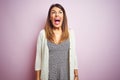 Young beautiful woman standing over pink isolated background angry and mad screaming frustrated and furious, shouting with anger