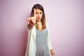 Young beautiful woman standing over pink isolated background Pointing with finger up and angry expression, showing no gesture Royalty Free Stock Photo