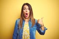 Young beautiful woman standing over yellow isolated background Surprised pointing with hand finger to the side, open mouth amazed Royalty Free Stock Photo