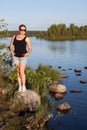 Young beautiful Caucasian woman standing on stone near lake water Royalty Free Stock Photo