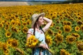 Young beautiful woman in a straw hat and with a bouquet of flowers in a field of sunflowers Royalty Free Stock Photo
