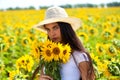 Young beautiful woman in a straw hat and with a bouquet of flowers in a field of sunflowers Royalty Free Stock Photo