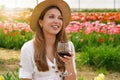 Young beautiful woman with straw hat drinking glass of red wine over flowered background looking to the side with happy face Royalty Free Stock Photo