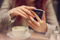 Young beautiful woman in a street cafe, is busy with her cell phone, close up at hands holding mobile phone Royalty Free Stock Photo