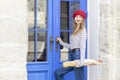 Young beautiful woman in striped shirt and red beret at the entrance to a store. Royalty Free Stock Photo
