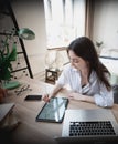 Young beautiful woman student with digital tablet and laptop studying working at home at the table Royalty Free Stock Photo