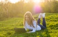 Young beautiful woman student with a laptop lies on the grass, in sunset Royalty Free Stock Photo