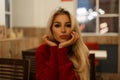 Young beautiful woman in stylish red sweater sits in cafe Royalty Free Stock Photo