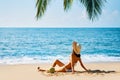 Young beautiful woman sunbathe and relax sitting alone on tropical beach