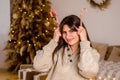 Young pretty woman in sweater, dark hair laughing with red white candy canes, against background of bed, Christmas tree Royalty Free Stock Photo